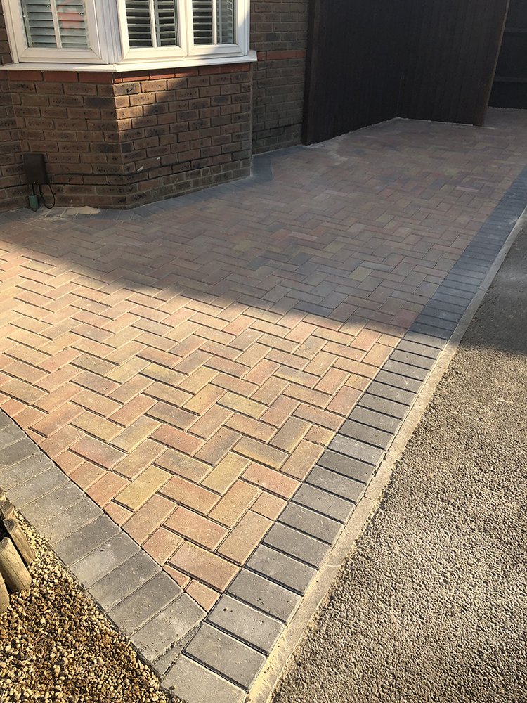 Buff herringbone block paved driveway with a charcoal double border