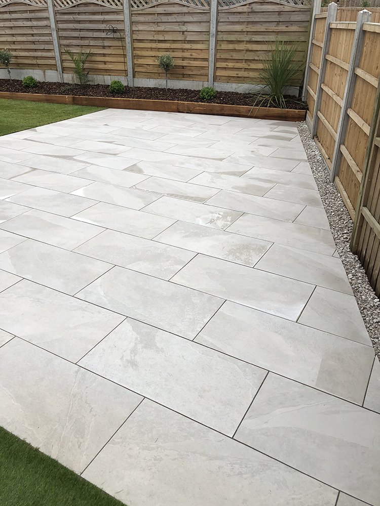 Pale grey large format porcelain patio with a gravel margin