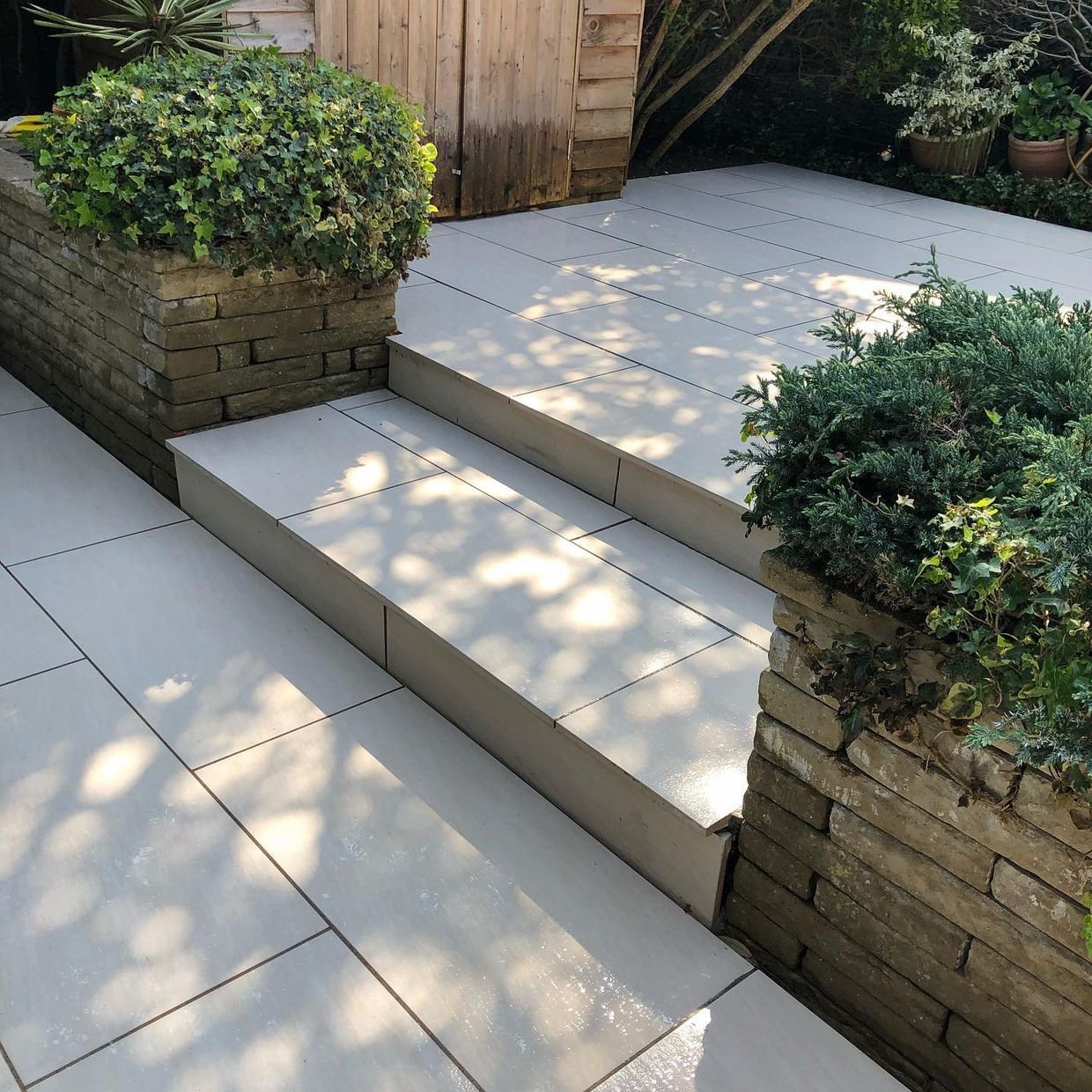 Smooth grey porcelain patio with two steps and stone planters