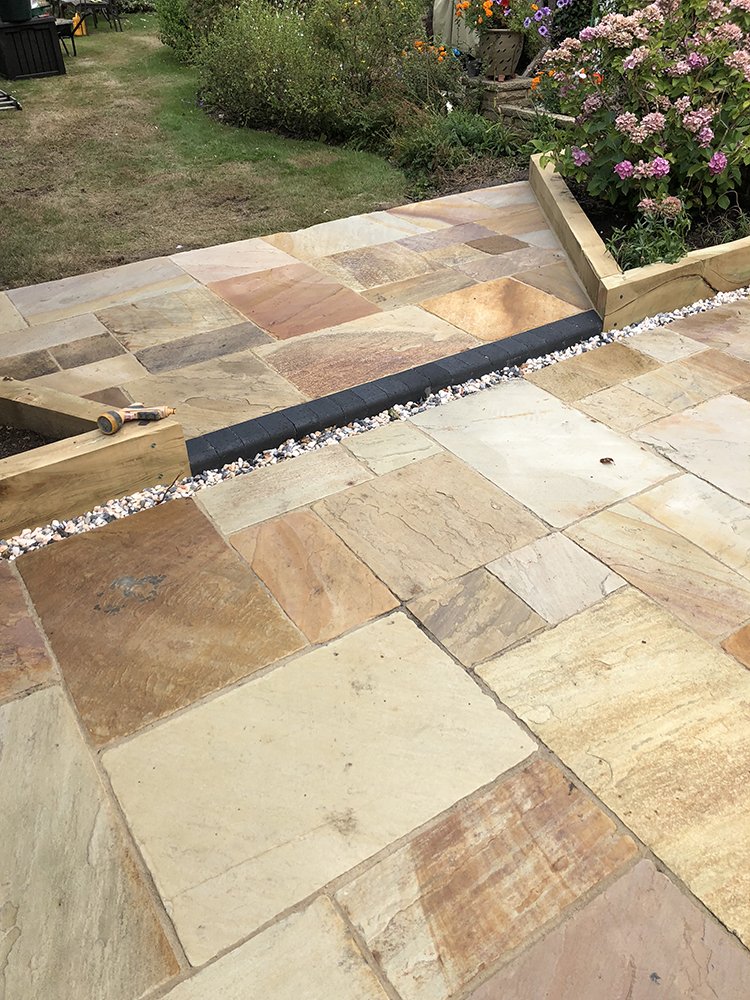 Multi-tone riven sandstone patio on two tiers with timber sleeper edging
